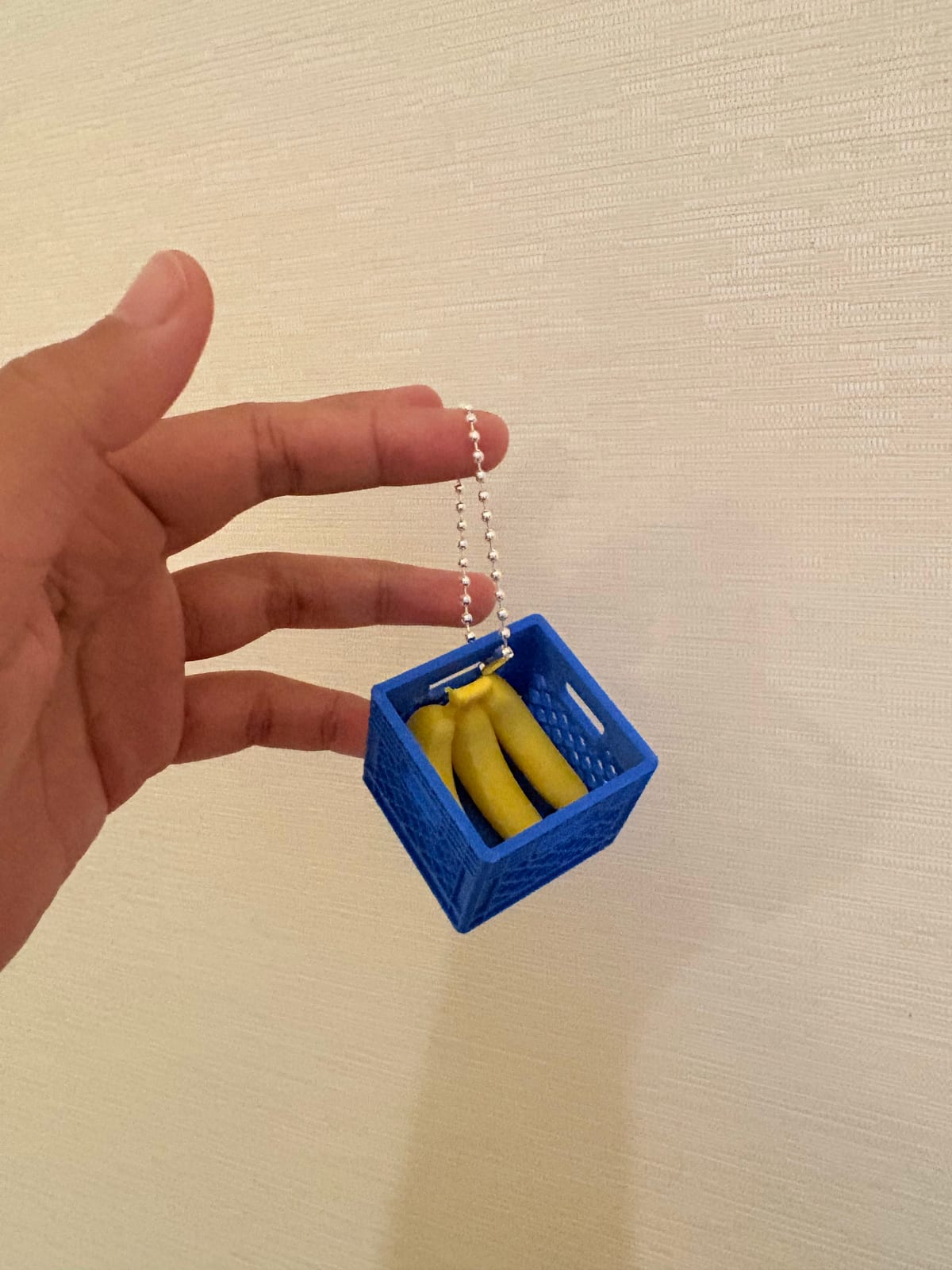 Blue fruit crate keychain with bananas held up by its ball chain