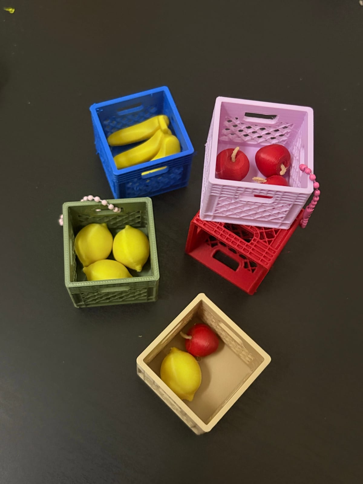 Fruit crate keychains in blue, pink, green and cream with different fruit inside
