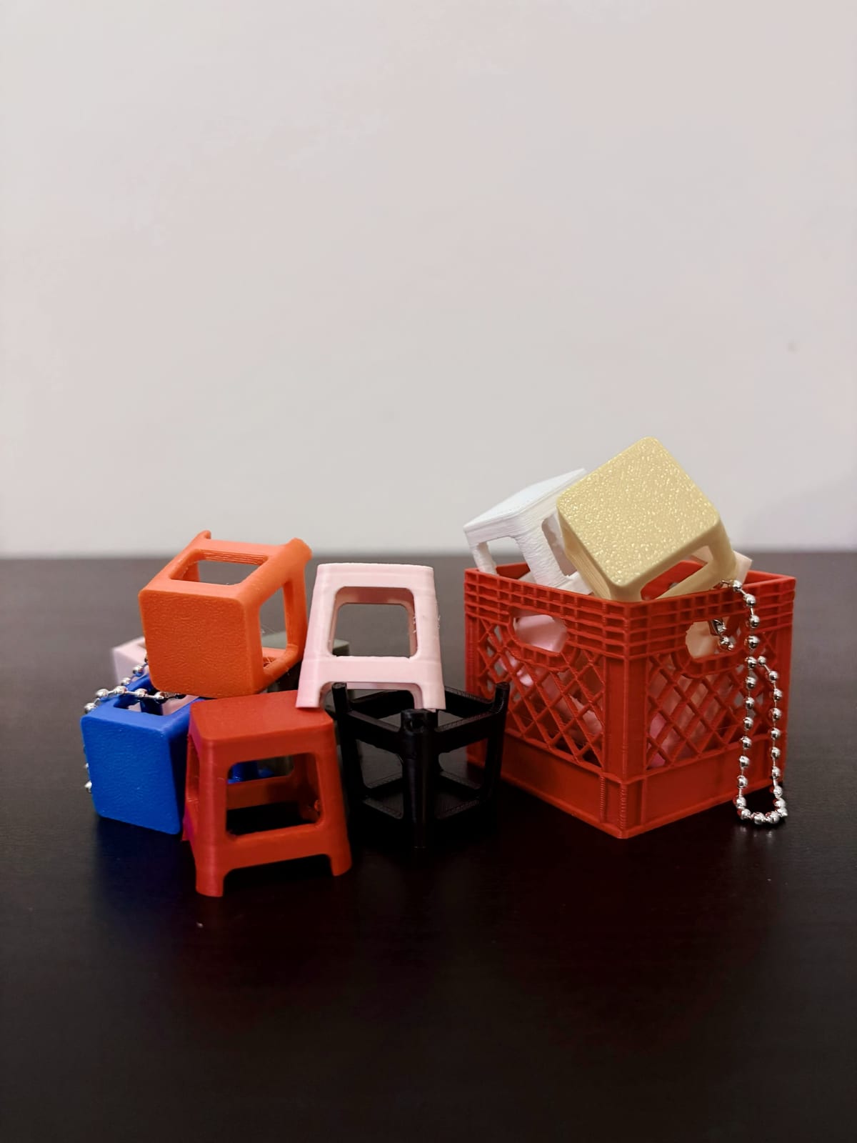 Red, blue and cream kenduri stool keychains next to fruit crate keychains