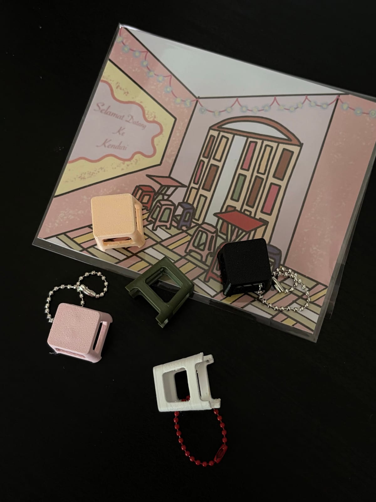 Kenduri stool keychains on a printed backing card